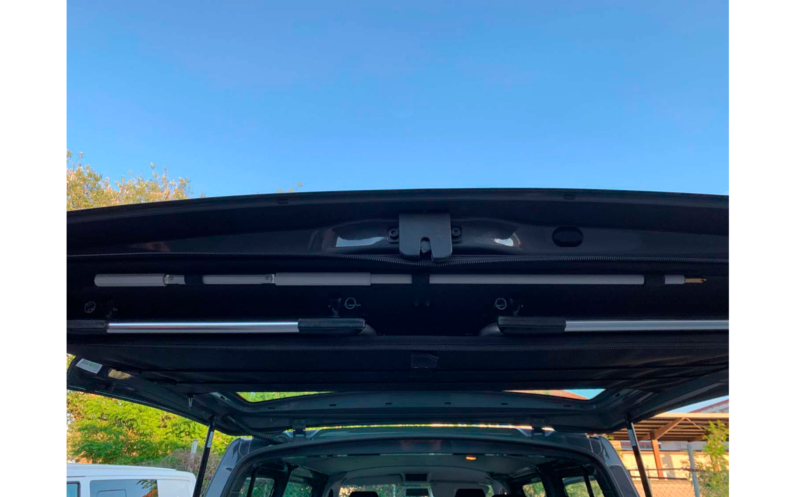 Asiento trasero abierto de un vehículo con vista hacia el exterior, cielo azul de fondo
