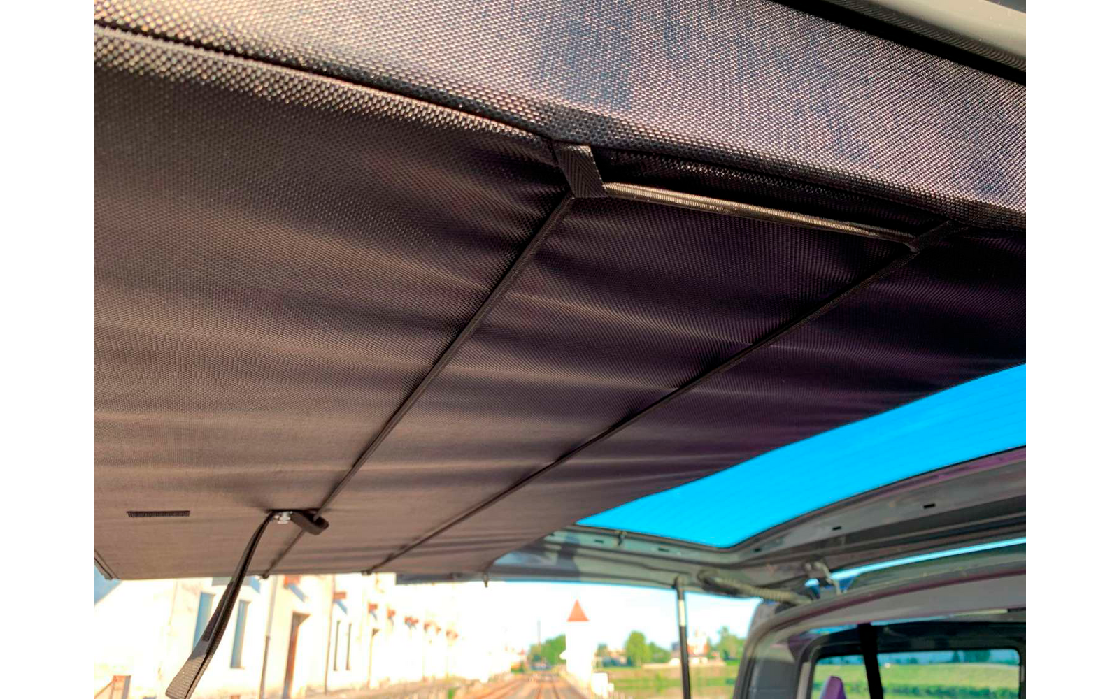 Toldo extendido sobre un vehículo, con edificios y cielo visibles debajo