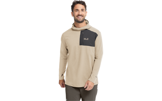 Mann mit kurzen dunklen Haaren und kurzem Bart, steht frontal, trägt beige Kapuzenpullover mit langen Ärmeln und schwarzer Brusttasche links sowie dunkle Hose