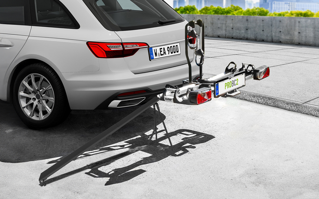 Weißer Kombi mit montiertem Fahrradträger auf dem Parkplatz, Stadt im Hintergrund