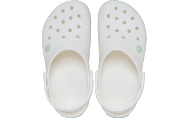 Paar crèmekleurige clogs, bovenaanzicht, ventilatiegaten, hielbandjes en groen rond logo aan de buitenkant