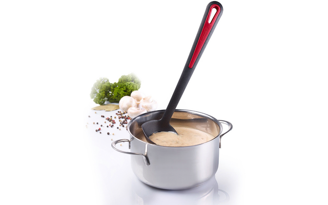 Edelstahlkochtopf mit hellbrauner cremiger Flüssigkeit und schwarzem Kochlöffel mit rotem Griff; daneben Brokkoliröschen, weiße Champignons und verstreute bunte Pfefferkörner auf weißem Hintergrund