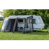 Witte caravan met een grijze voortent met grote ramen op een groen gazon voor bomen