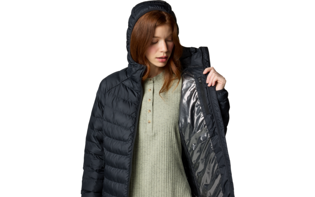 Femme aux cheveux roux portant une doudoune noire à capuche, tenant la veste ouverte ; pull vert en maille avec patte de boutons visible