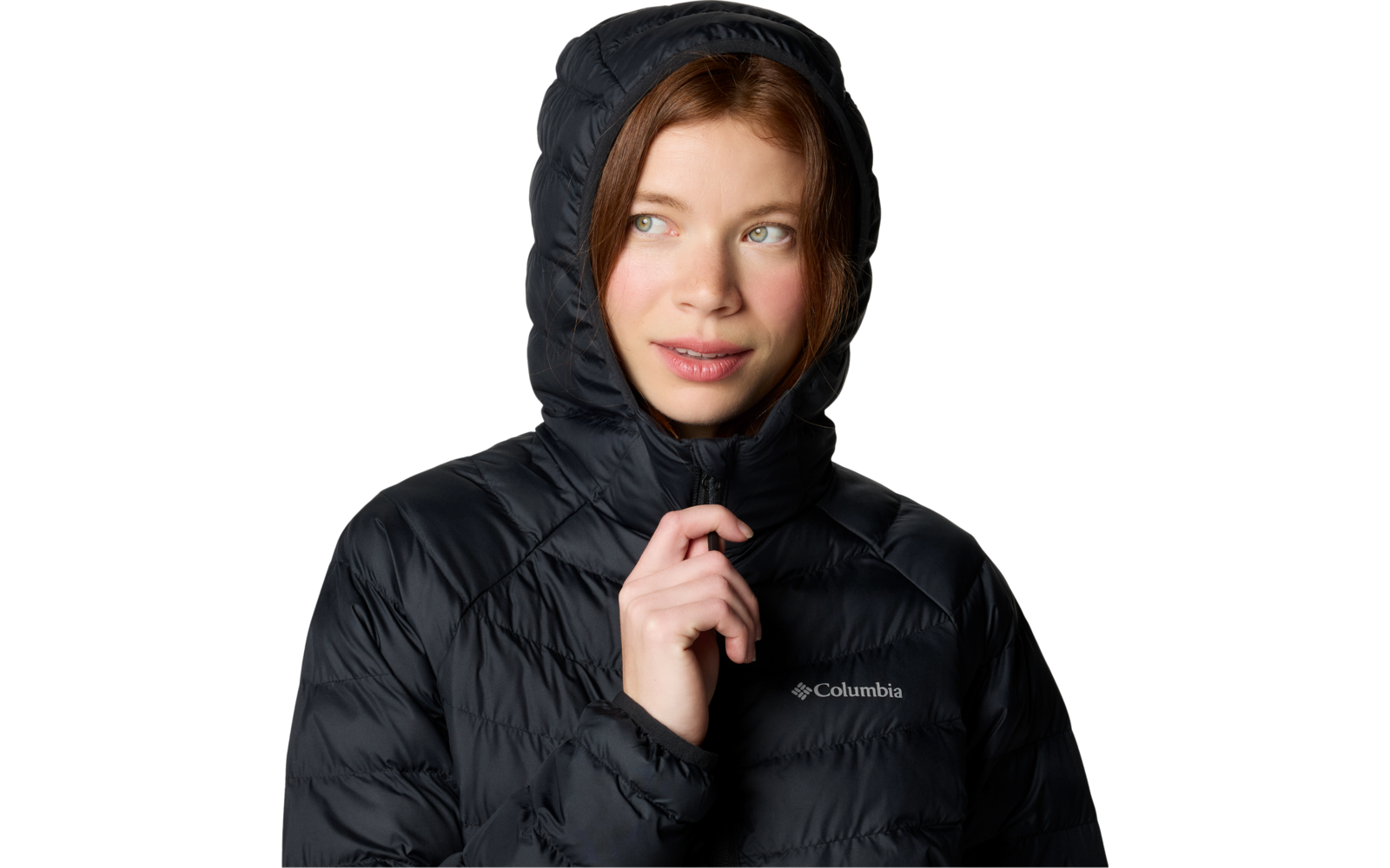 Personne portant une doudoune noire avec capuche relevée, main droite tenant la fermeture éclair près du menton, regard légèrement vers la gauche, logo Columbia visible sur la poitrine, fond blanc