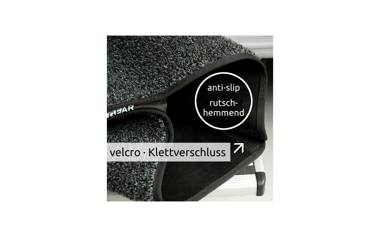Nahaufnahme eines grauen, strukturierten Teppichstücks mit schwarzem Klettverschluss auf einer Metallstufe; sichtbare Texte 'anti-slip rutschhemmend' und 'velcro · Klettverschluss'