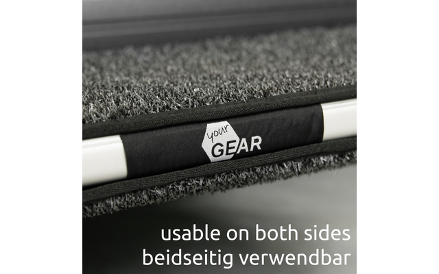 Nahaufnahme einer grauen, strukturierten Matte mit schwarzem Riemen, weißem Sechseck-Logo 'your GEAR' auf dem Riemen und einer weißen Stange; unten der Text 'usable on both sides beidseitig verwendbar'