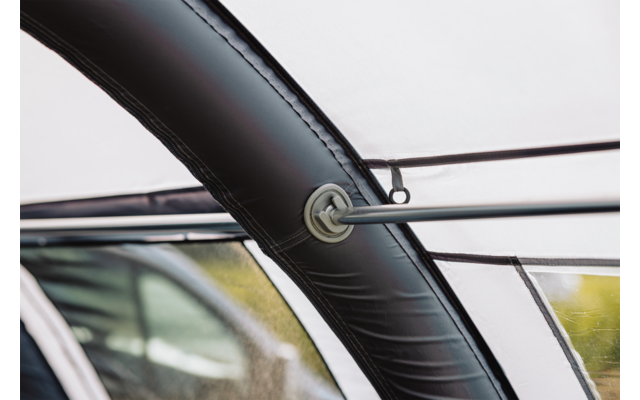 Schwarzer, gebogener zylindrischer Rahmen mit Naht; zwei dünne Metallstangen stecken durch eine runde Öse; durchsichtige Plane mit Wassertropfen; unscharfes Auto im Hintergrund