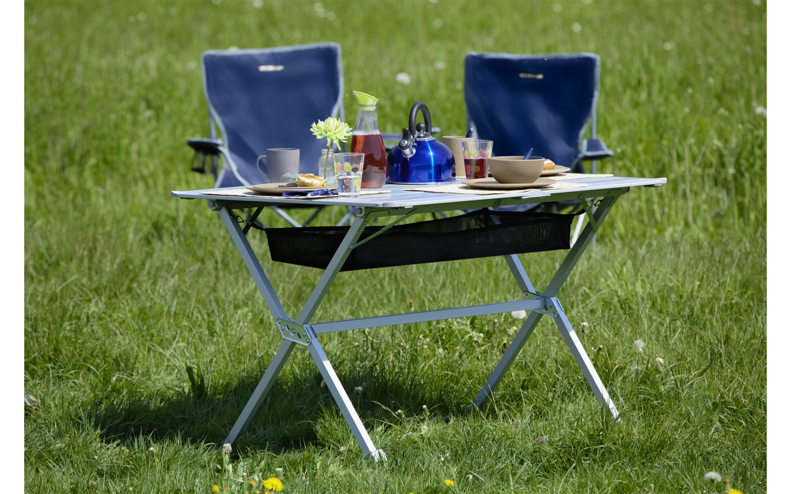 Table de jardin pliante avec des boissons et deux chaises bleues sur une pelouse
