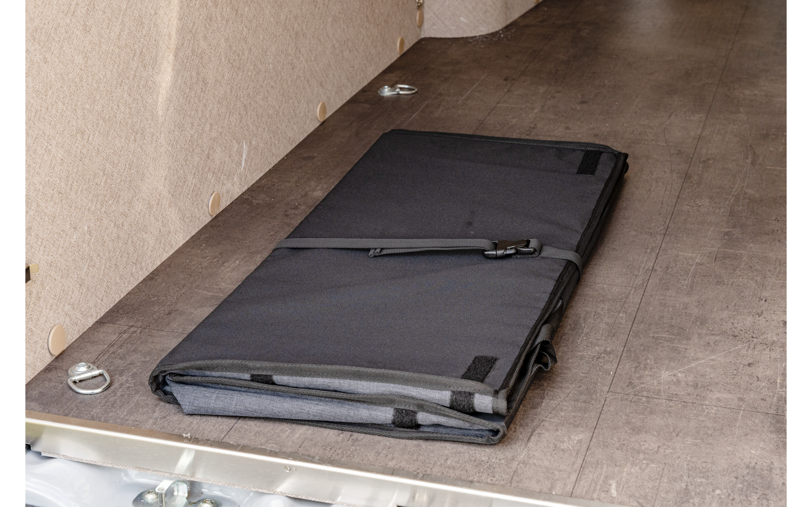 Schwarze faltbare Gymnastikmatte liegt auf grauem Boden