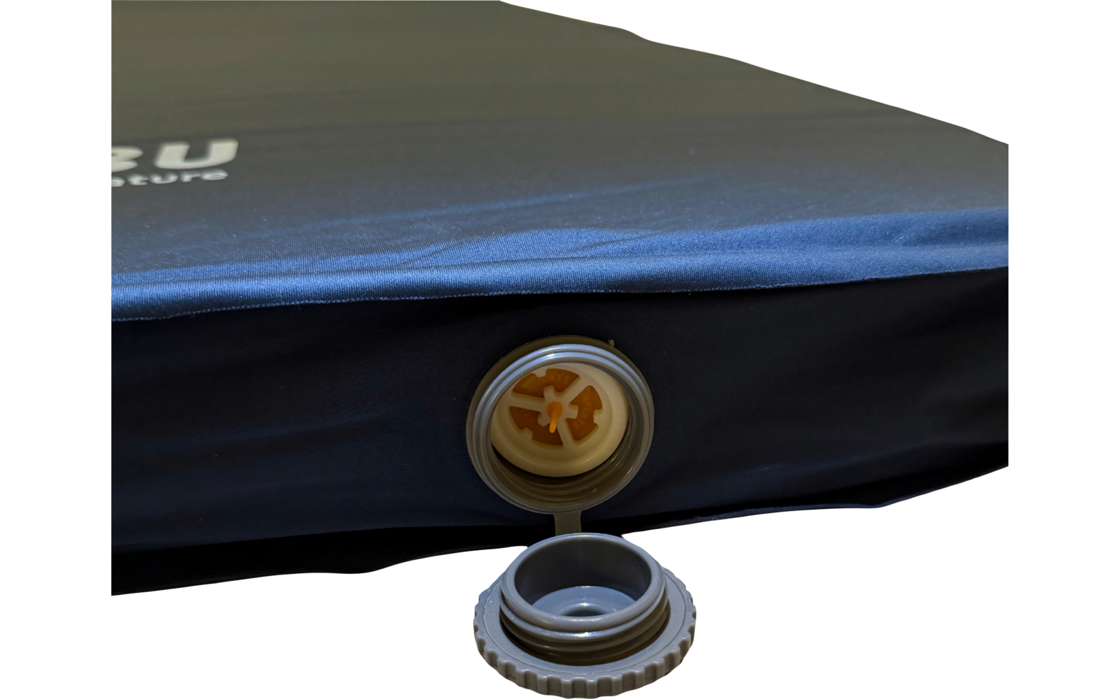 Nahaufnahme einer blau-schwarzen Luftmatratze mit offenem Ventil und abgenommenem Schraubdeckel