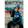 Een kind met fietshelm en handschoenen houdt een zwarte drinkfles naar de camera; onscherpe achtergrond, gevallen bladeren op de grond