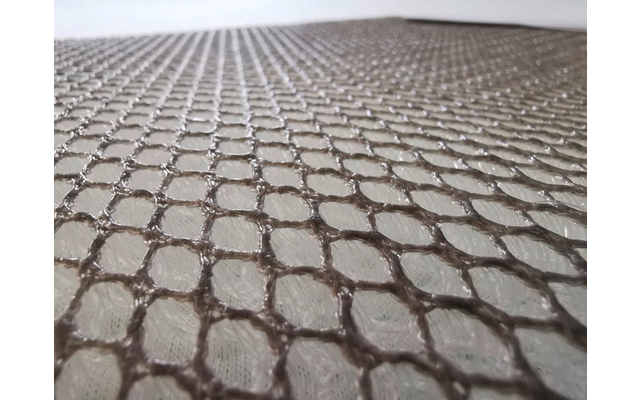 Close-up van een bruin net over een lichte, gestructureerde ondergrond, voorgrond scherp, achtergrond onscherp