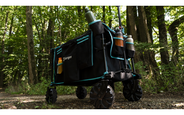 Schwarzer klappbarer Wagen mit zwei Flaschen, steht auf einem Waldweg