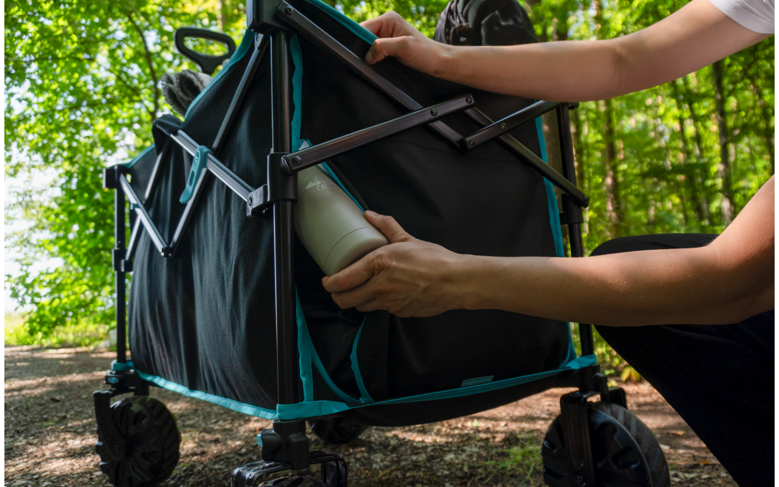 Person legt ein Buch in eine Tasche, ein Kinderwagen steht im Hintergrund