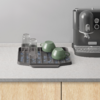 Capsules op tray naast espressomachine op keukenblad