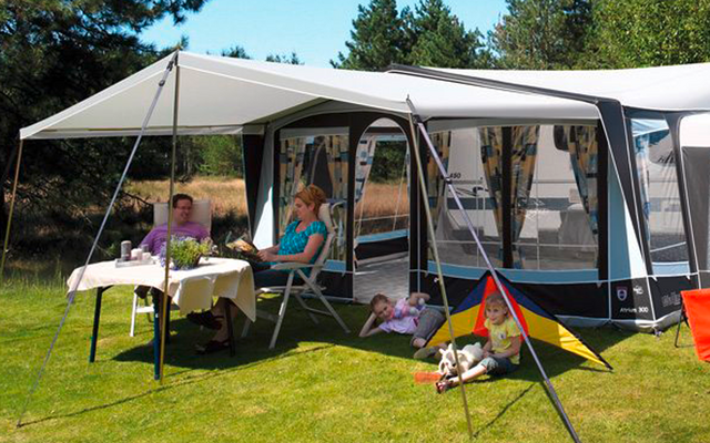 Caravana con toldo desplegado y tres personas sentadas afuera