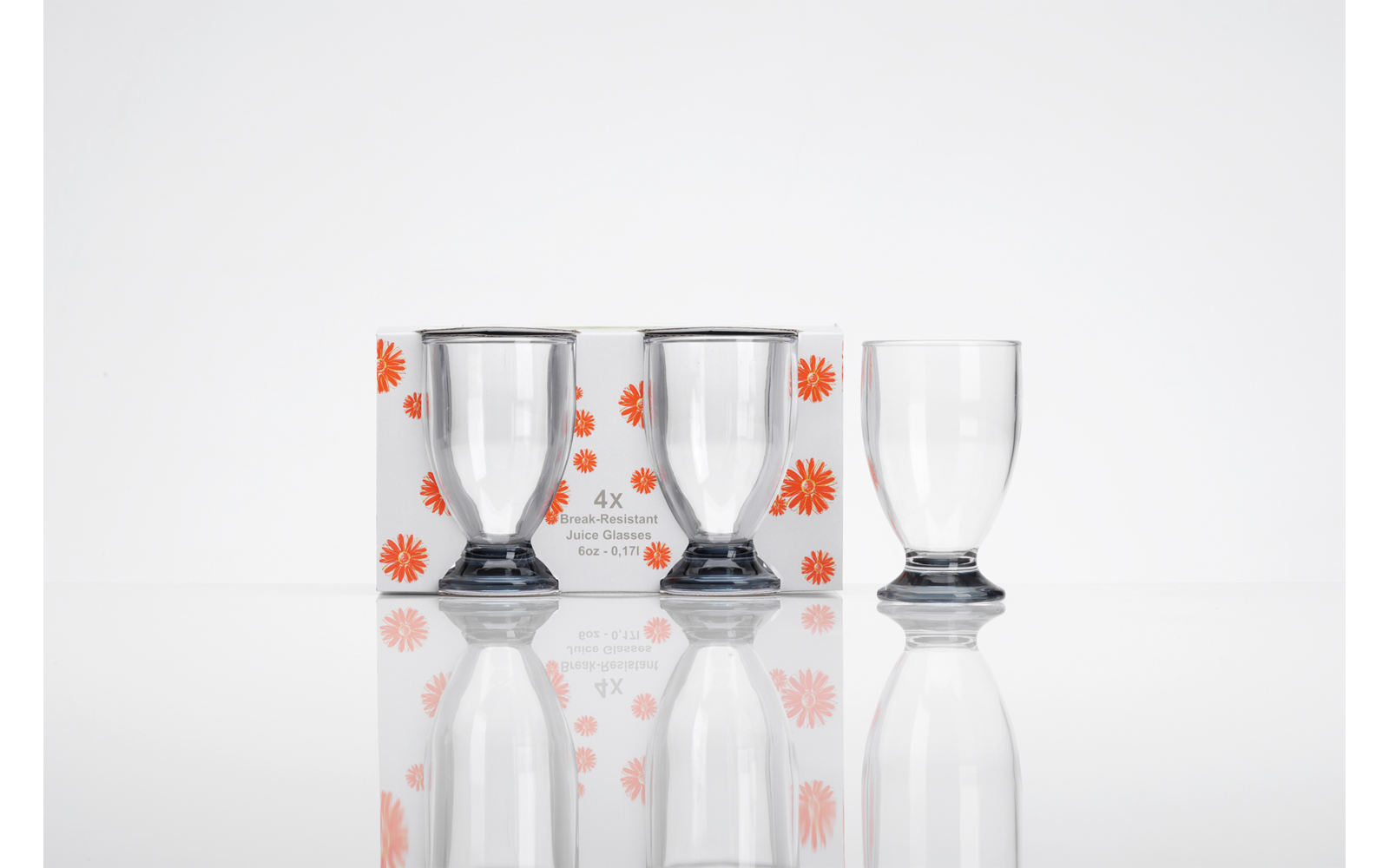 Drei durchsichtige Trinkgläser mit dunklem ringförmigem Fuß vor einer weiß bedruckten Verpackung mit orangenen Blumen und der Aufschrift "4x" auf weißem Hintergrund