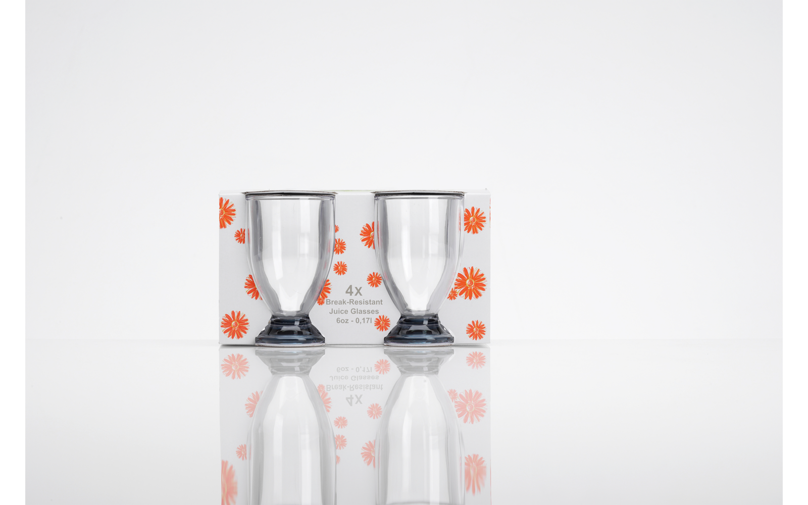 Zwei klare Gläser in weißer Verpackung mit orangefarbenem Blumenmuster, auf spiegelnder Oberfläche