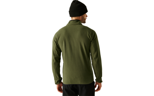 Ein Mann steht mit dem Rücken zur Kamera, trägt eine grüne Jacke und eine schwarze Mütze