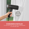 Hand hält ein schwarzes Handdampfgerät an eine weiße Hemdbluse mit Knöpfen; rundes Emblem auf der Bluse mit dem Text '30 SECONDS HEAT UP TIME'; roter Balken mit weißer deutscher Schrift am unteren Bildrand