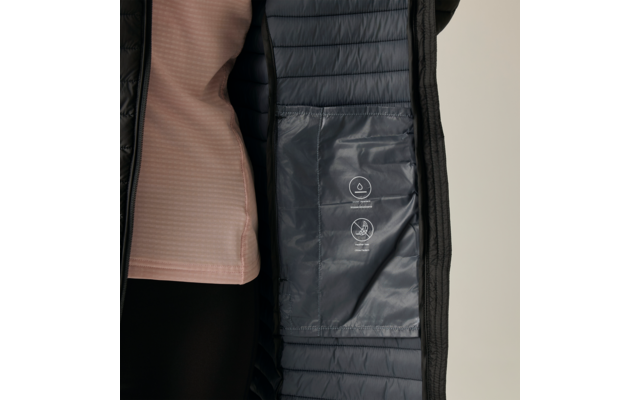 Interno di un cappotto trapuntato blu scuro aperto con tasca interna e due pittogrammi di cura bianchi; a sinistra top rosa chiaro parzialmente visibile e leggings neri, sfondo neutro