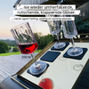 Three wine glasses with red wine on an illuminated wooden surface, garden landscape in the background