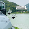 View of a camper van by a lake with mountains in the background