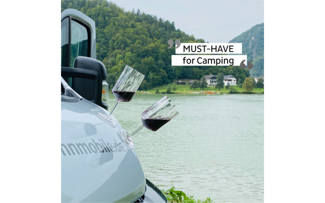 View of a camper van by a lake with mountains in the background