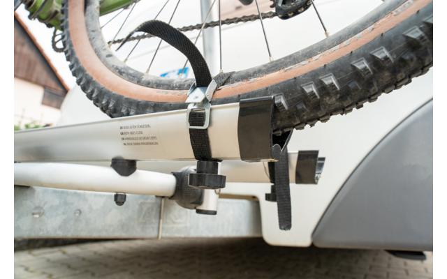 Gomma e telaio di una bicicletta su un portabici posteriore montato su un'auto, fissati con una cinghia e una staffa metallica