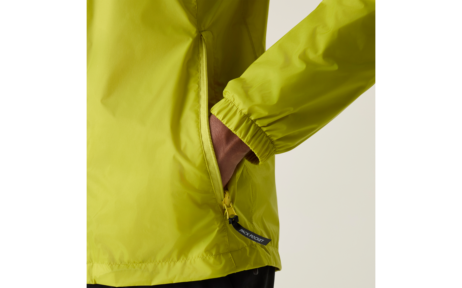 Detailaufnahme einer hellgrünen Regenjacke, Hand in der seitlichen Reißverschlusstasche, elastisches Ärmelbündchen sichtbar