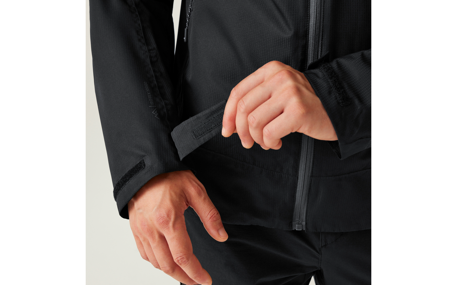 Hände, die eine Klettverschlusslasche an der Ärmelmanschette einer schwarzen Jacke anpassen