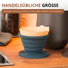 Support de filtre pliable en silicone bleu avec filtre en papier brun sur un plan de travail en bois ; en arrière-plan un bocal en verre de grains de café, une bouilloire foncée, un torchon plié et un coin d'ordinateur portable ; texte superposé « HANDELSÜBLICHE GRÖSSE » et « GEIGNET FÜR ALLE HANDELSÜBLICHEN PAPIERFILTER GRÖSSE 2 »