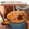 Gros plan d'un dripper en silicone bleu avec un filtre en papier brun et du marc de café; de l'eau chaude est versée d'une bouilloire métal; récipient en verre flou en arrière‑plan; en haut le texte SEHR HITZEBESTÄNDIG et BESTÄNDIG BIS 200 °C - IDEAL FÜR KAFFEE DIREKT AUFGEBRÜHT
