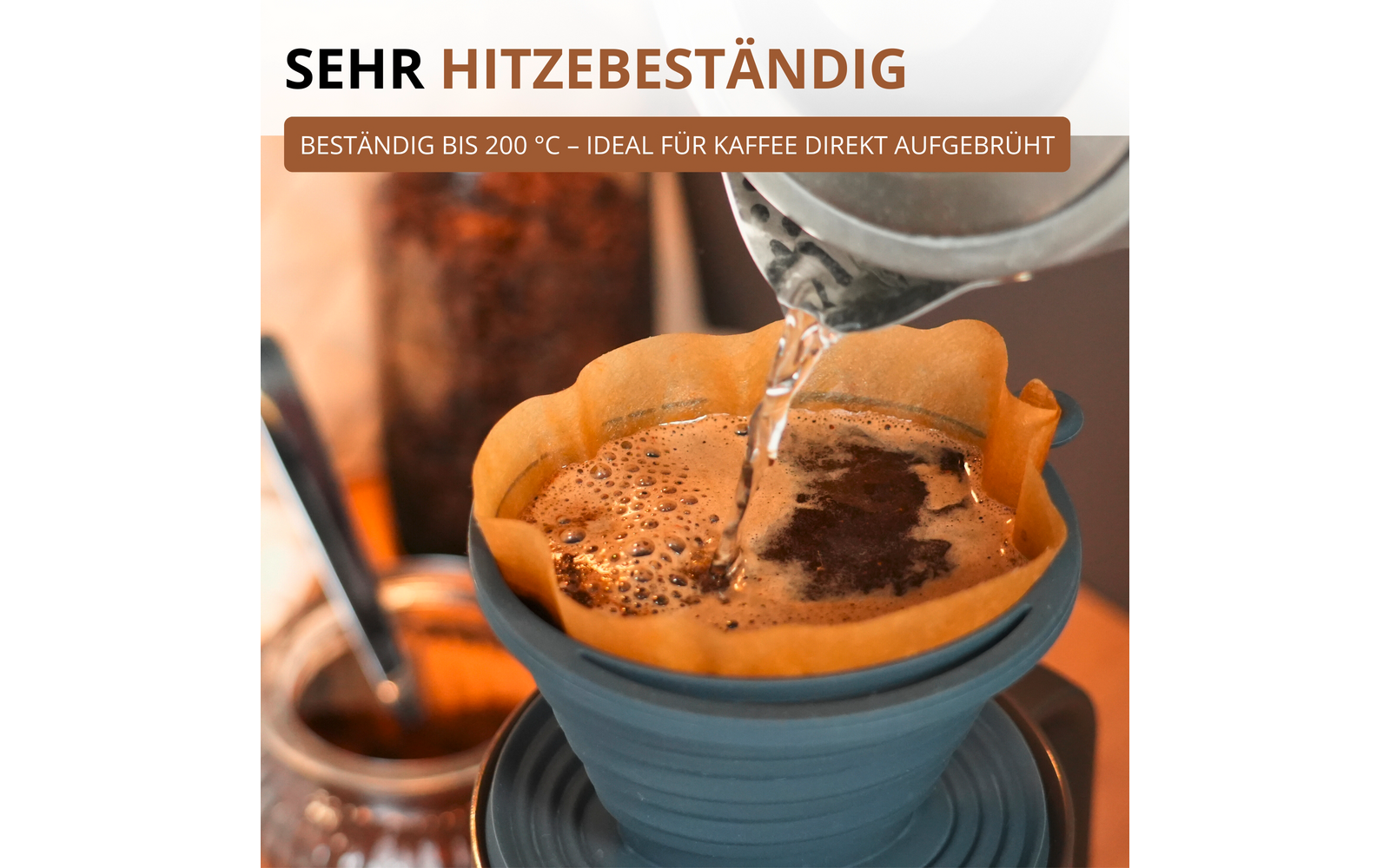 Gros plan d'un dripper en silicone bleu avec un filtre en papier brun et du marc de café; de l'eau chaude est versée d'une bouilloire métal; récipient en verre flou en arrière‑plan; en haut le texte SEHR HITZEBESTÄNDIG et BESTÄNDIG BIS 200 °C - IDEAL FÜR KAFFEE DIREKT AUFGEBRÜHT