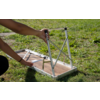 Two hands unfolding metal legs of a folding table with wooden top and white frame on grass