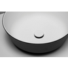 Lavabo redondo blanco con exterior negro y tapón de desagüe circular sobre fondo gris