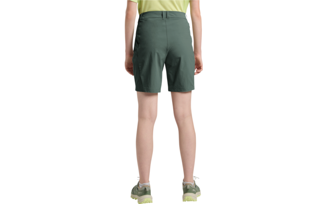 Rückenansicht einer stehenden Person von der Taille bis zu den Füßen, mit hellgrünem T‑Shirt, dunkelgrünen knielangen Shorts und graugrünen Sportschuhen mit hellgrünen Sohlen