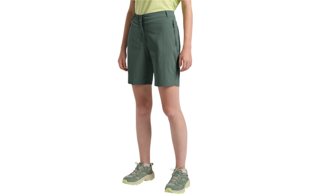 Untere Körperhälfte einer stehenden Person mit dunkelgrünen knielangen Shorts, gelbem Oberteil sichtbar am Bund, hellgrünen Sportschuhen mit hellgelben Sohlen und seitlich hängenden Händen