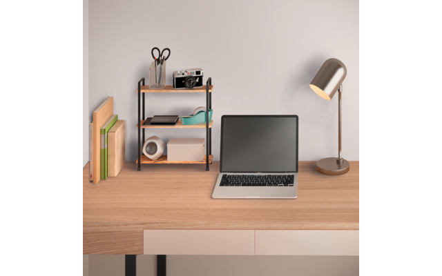 Holztisch mit offenem Laptop (schwarzer Bildschirm), rechts eine Metall-Schreibtischlampe, links ein kleines Regal mit Schere, Stifthalter, Kamera und Klebeband; Bücher und Ordner am linken Rand