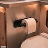 Toiletrol op een zwarte houder gemonteerd op een metalen en houten paneel naast de toiletbril