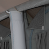 Close-up van een lichtgrijs cilindrisch stofelement met zichtbare naden naast donkergrijze stofpanelen, een ritssluiting, klittenbandflappen en geplooide gordijnplooien