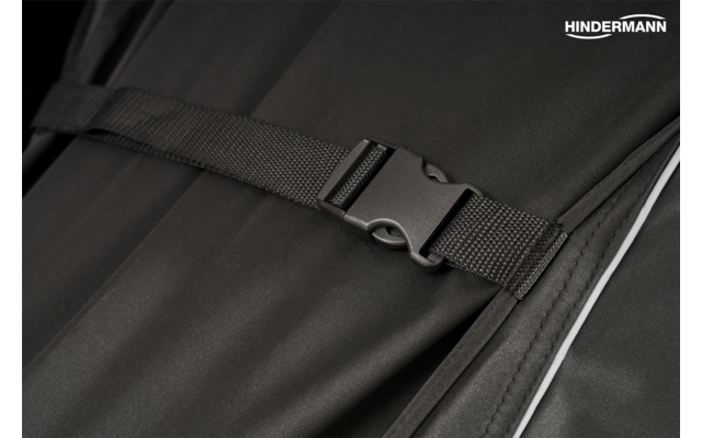 Nahaufnahme einer schwarzen Kunststoff-Steckschnalle an einem schwarzen Gurt auf schwarzem Stoff, weiße Paspel rechts, weißes Markenlogo 'HINDERMANN' oben rechts