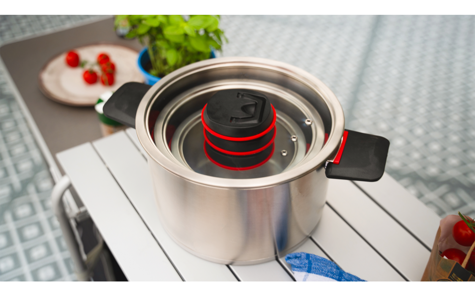 Une casserole avec de l'eau bouillante sur une cuisinière, avec un insert passoire contenant des pâtes rouges au-dessus