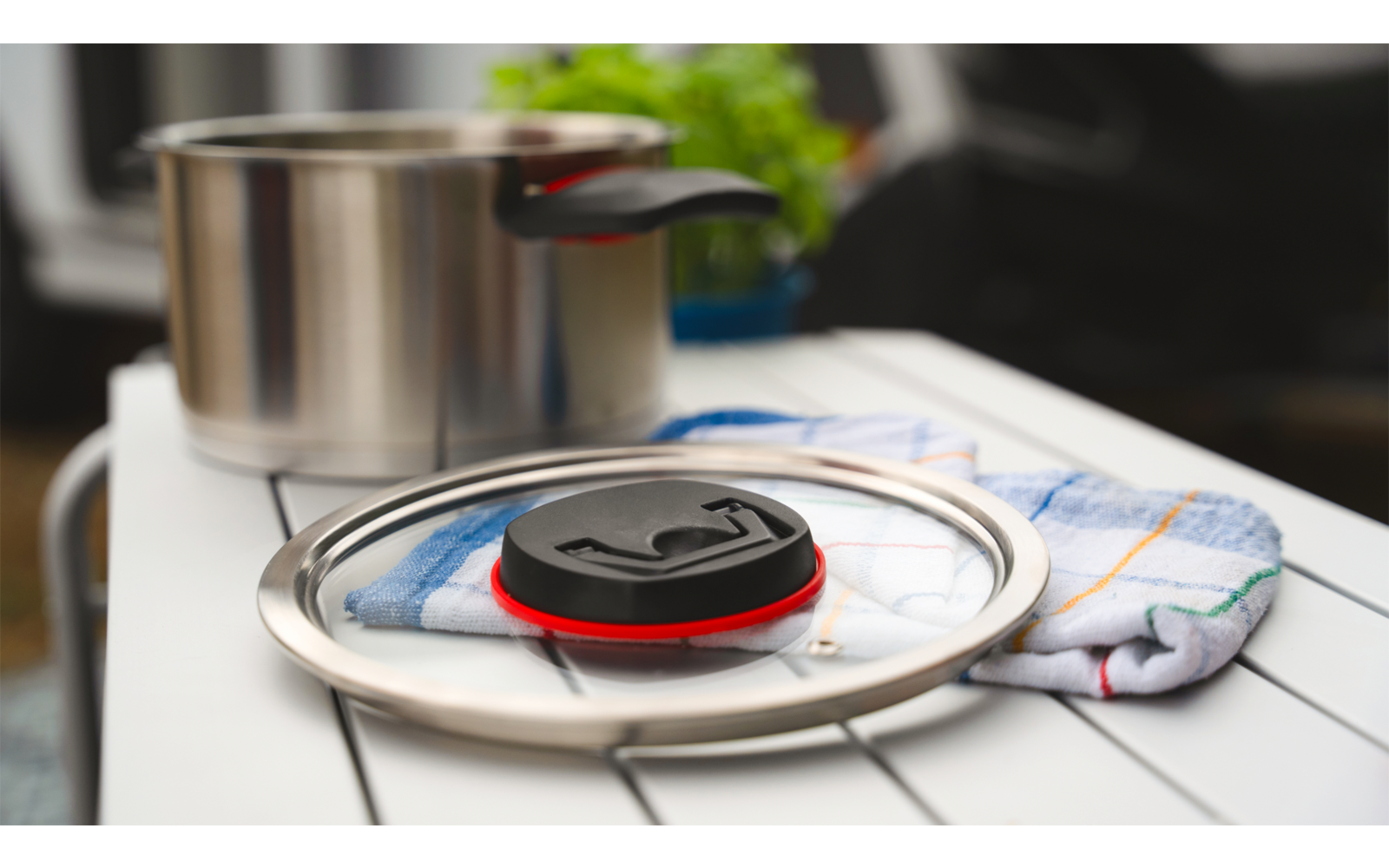 Bouilloire avec couvercle sur la cuisinière, à côté une casserole et une serviette sur le comptoir blanc