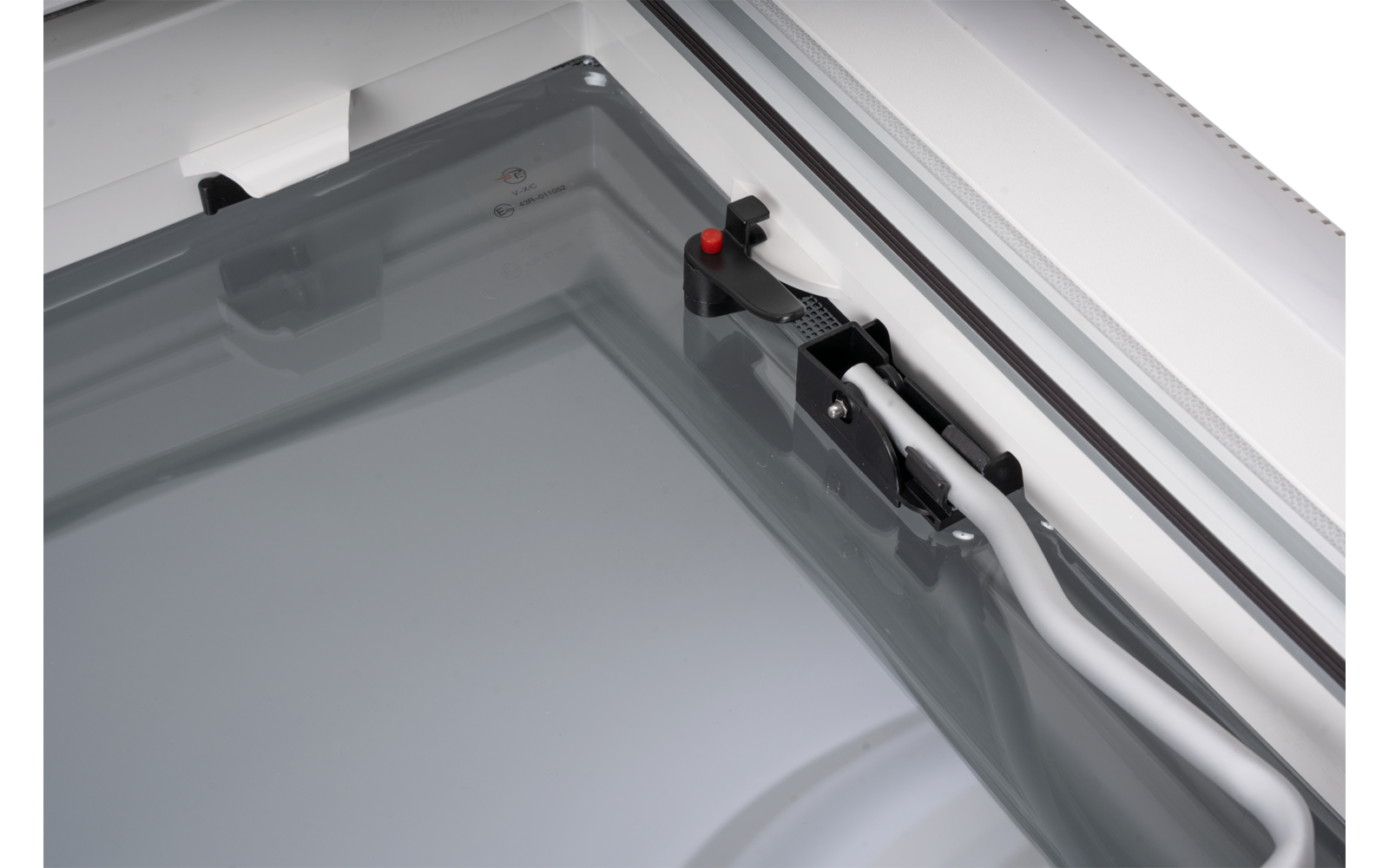 Close-up of a gray glass panel in a white metal frame with a black plastic clip with a red button and two white cables