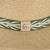 Beige geflochtener Strohhut mit grün-weißem Stoffband und rundem Metallknopf an einer Lasche