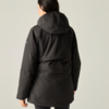 Person seen from the back wearing a black hooded jacket against a light background