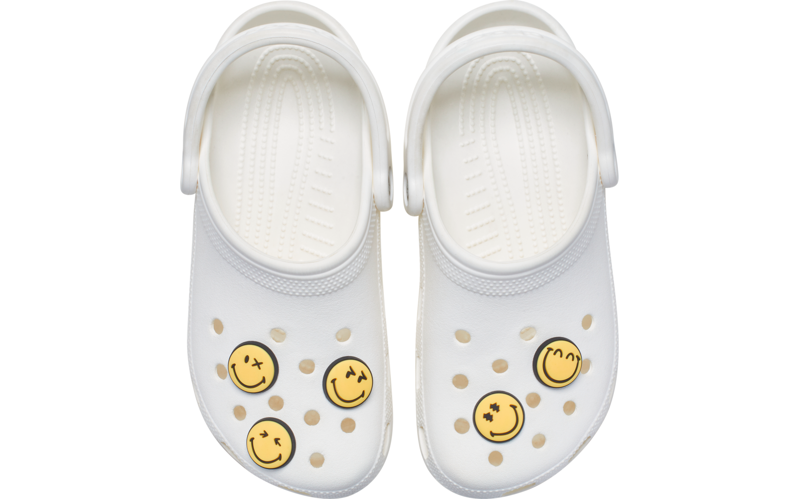 Par de zuecos blancos vistos desde arriba, orificios de ventilación, correas en el talón, cuatro decoraciones redondas amarillas con trazos faciales negros
