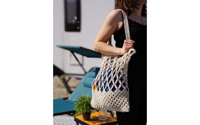 Donna che porta una borsa a rete con verdure fresche, tavolo con sedia e quadro incorniciato sullo sfondo